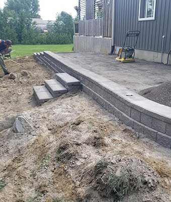 landscape construction of new retaining wall with stone steps and patio