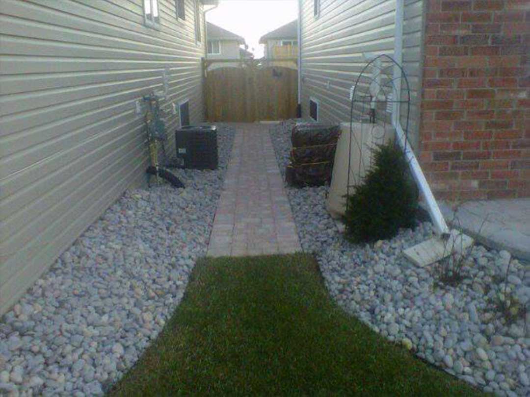 landscape construction between two houses including interlocking stone pathway leading to wooden gates