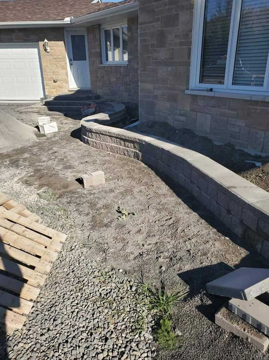 landscape construction of stone retaining wall and steps in front of residence